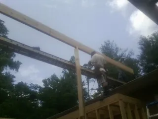 Carpenter setting a ridge beam over a new addition frame — Ice Dam Removal by Roofing Brothers in Cherokee