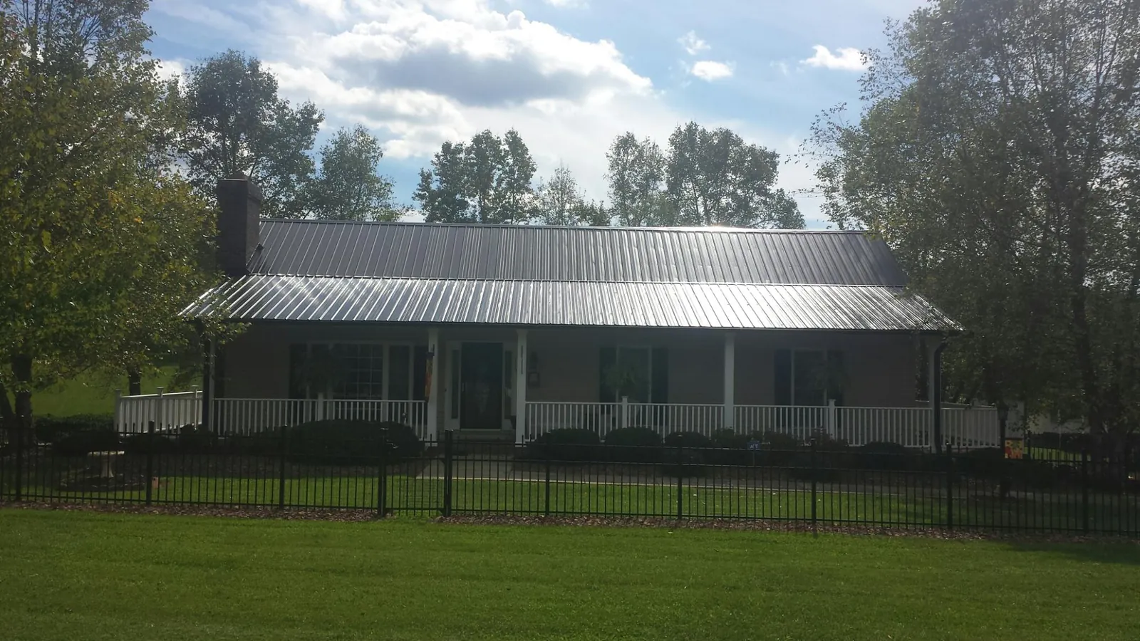 Gray metal roof on a brick ranch with a full width front porch — Gutter Guard Installation work by our crew in Cherokee